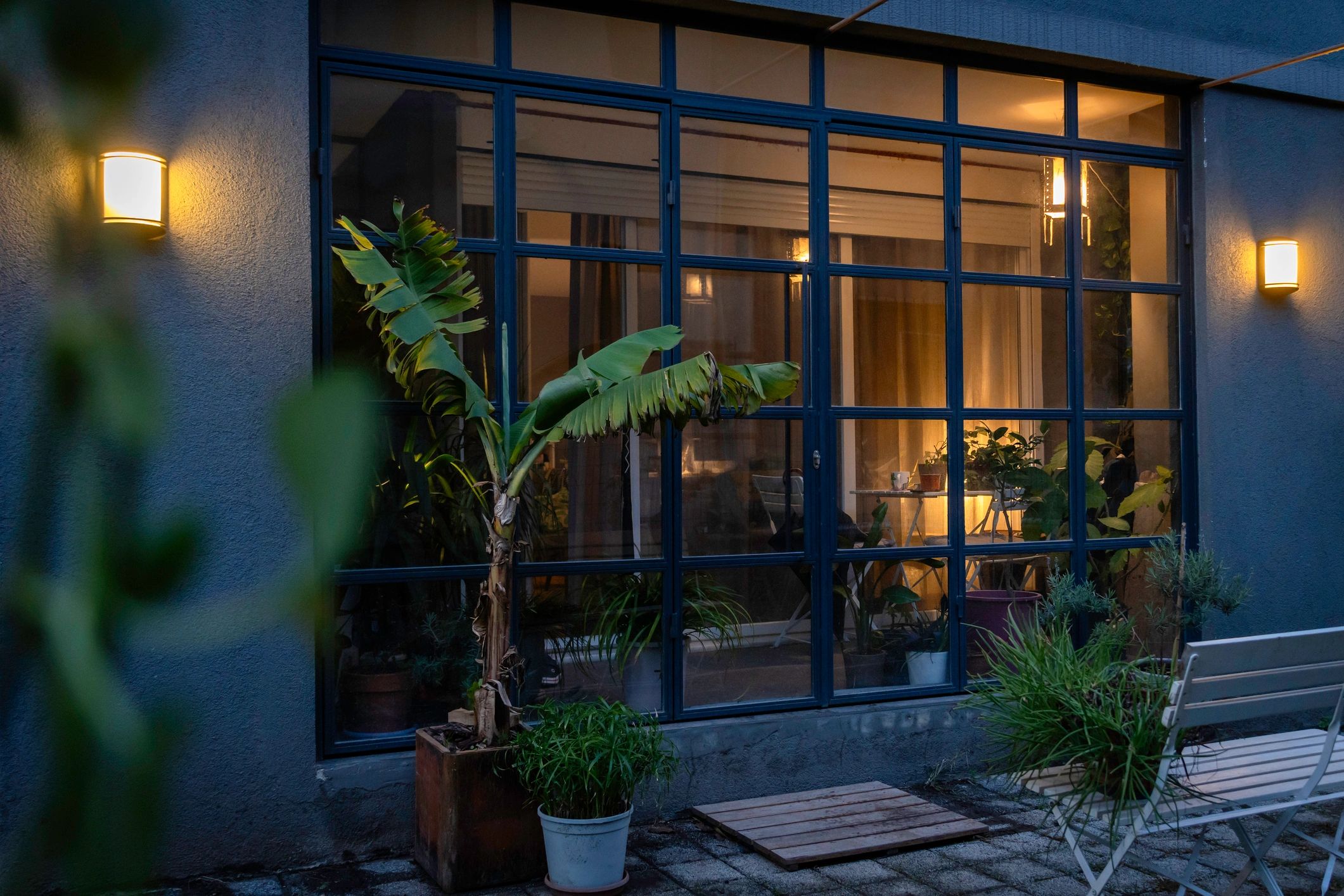 Cozy modern home entrance with large glass doors and lush plants.