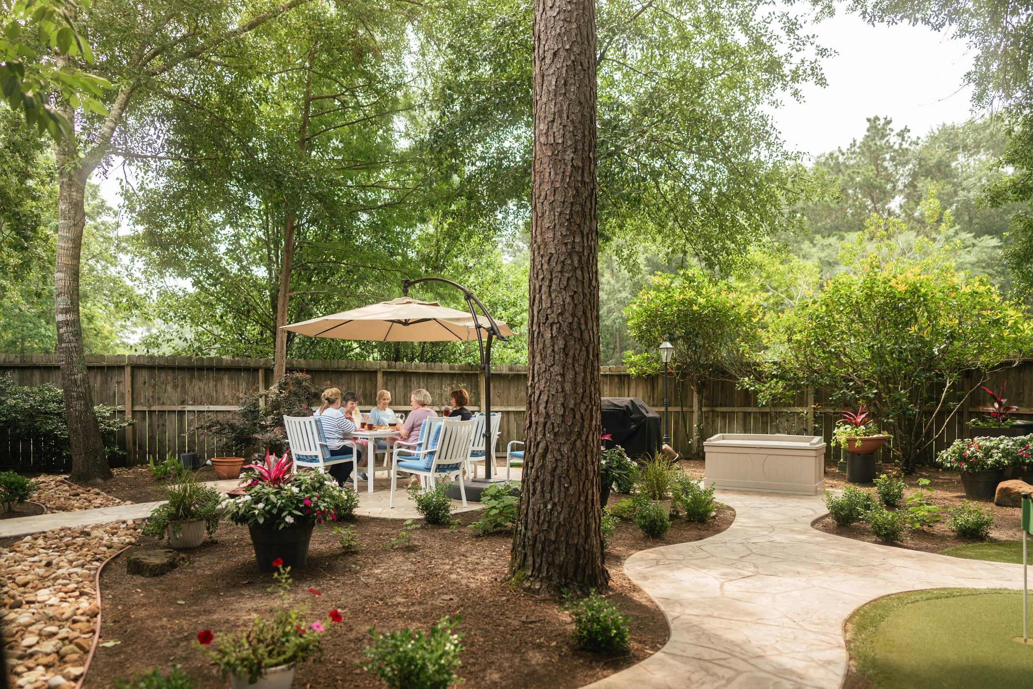 People relaxing at an outdoor café surrounded by trees and greenery.