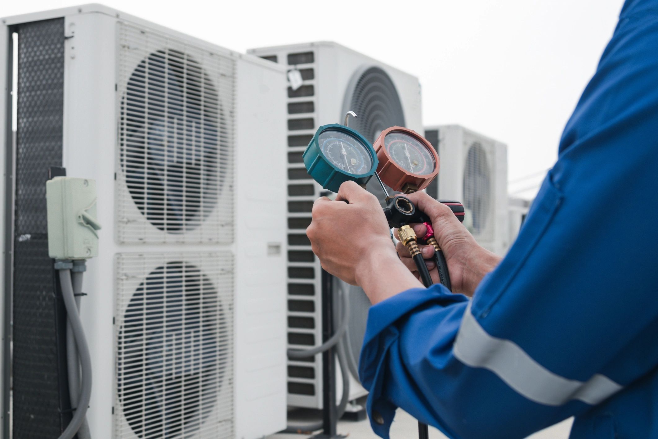 Technician checking air conditioner gauges outdoors.